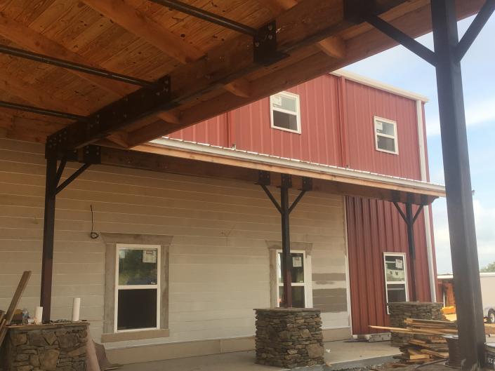 The front porch has plenty of covered space for people to gather and visit. It features natural elements like wood and stones that are complimented with rich earth tones and black iron accents.